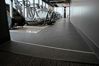 A row of cardio equipment, including treadmills and elliptical trainers, in a corporate fitness center.