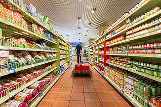 An employee in the Alnatura supermarket pulls a pallet truck across the floor, which has been decoupled with REGUPOL sound products.