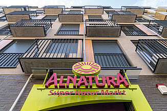 Main entrance of the Alnatura organic supermarket with flats above.